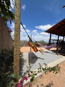 a hammock hanging from a palm tree on the beach at Chalé Vista Encanto dos Montes in Monte das Gameleiras
