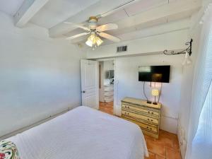 een slaapkamer met een wit bed en een flatscreen-tv bij Baked Beach Bungalow in St. George Island