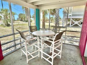 een tafel en stoelen op een afgeschermde veranda bij Baked Beach Bungalow in St. George Island