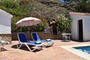 two chairs and an umbrella next to a swimming pool at Finca La Jara with private Pool in Cómpeta