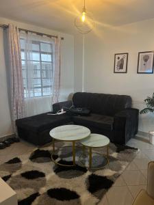 ein Wohnzimmer mit einer schwarzen Couch und zwei Tischen in der Unterkunft El luxe Homes Muthiga in Kiambu