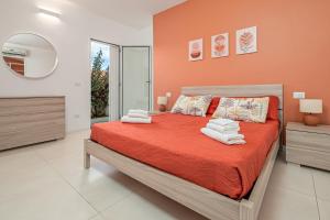 Schlafzimmer mit einem Bett mit orangefarbenen Wänden und einem Spiegel in der Unterkunft Cormorani - Appartamento 7 in Golfo Aranci