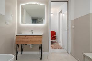 ein Badezimmer mit einem Waschbecken, einem Spiegel und einem roten Stuhl in der Unterkunft Cormorani - Appartamento 7 in Golfo Aranci + 20 Fotos