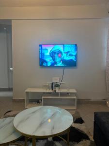 ein Wohnzimmer mit einem Tisch und einem Fernseher an der Wand in der Unterkunft El luxe Homes Muthiga in Kiambu
