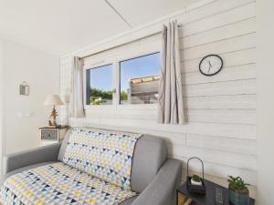 ein Wohnzimmer mit einer Couch und einer Uhr an der Wand in der Unterkunft Chalet pour 6, domaine avec piscine in Saint-Hilaire-de-Riez