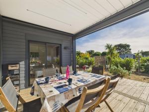 ein Esszimmer mit Tisch und Stühlen auf einer Terrasse in der Unterkunft Chalet pour 6, domaine avec piscine in Saint-Hilaire-de-Riez