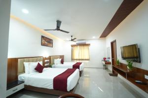 una habitación de hotel con dos camas y un televisor de pantalla plana en Hotel Nanda Mohan Residency, en Tirupati