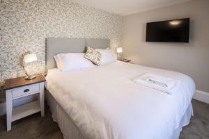 a bedroom with a white bed with a tv on the wall at La Croix Guest House in Isle of Jersey