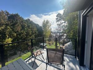 蒙特贝罗Le Refuge de la Rivière Proche du Parc Omega的阳台配有两把椅子和一张桌子