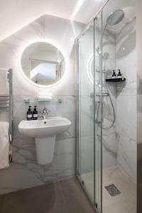 a white bathroom with a sink and a shower at La Croix Guest House in Isle of Jersey
