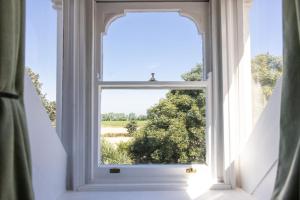 an open window with a view of a field at La Croix Guest House in Isle of Jersey +4 photos