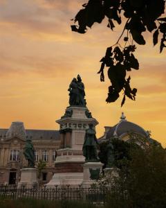 eine Statue vor einem Gebäude mit Sonnenuntergang in der Unterkunft Résidence du Lion in Belfort