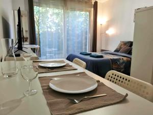 a dining room table with a plate and glasses on it at Studio Zen I Hypercentre I Parking privé I Patio I WIFI in Salon-de-Provence