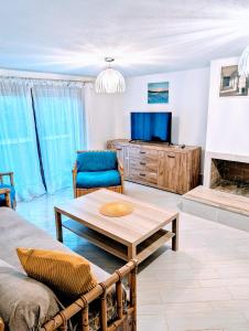 ein Wohnzimmer mit einer Couch, einem Tisch und einem Fernseher in der Unterkunft Casa Del Tramonto in Costa Paradiso