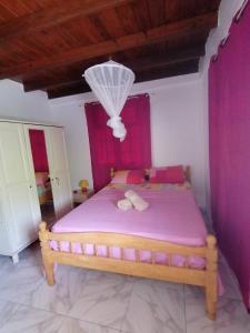a bedroom with a bed with pink sheets and a chandelier at Villa Océane in Dublanc