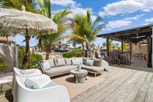 eine Terrasse mit weißen Möbeln und Palmen in der Unterkunft Kas Palma at Waterland's Village - Private pool! in Kralendijk