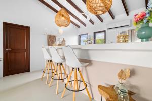 eine Küche mit drei weißen Barhockern und einer Theke in der Unterkunft Kas Palma at Waterland's Village - Private pool! in Kralendijk
