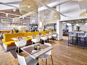 a restaurant with tables and chairs and a yellow couch at ibis La Roche Sur Yon Vendespace in Mouilleron-le-Captif