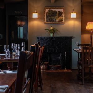 a fireplace in a restaurant with a table and chairs at The Three Swallows Cley in Cley next the Sea