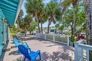 a deck with two blue chairs and palm trees at Toes in the Sand - 113 in Sarasota