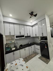 a kitchen with white cabinets and a black refrigerator at Aufa House in Padang Rengas