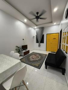 a living room with a ceiling fan and a table and chairs at Aufa House in Padang Rengas