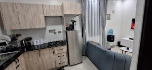 a kitchen with a refrigerator and a blue couch at Bliss Stay Ruaka in Ruaka