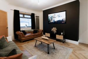 a living room with a couch and a tv on a wall at Marine Cottage 1 - With Private Hot Tub in Newbiggin-by-the-Sea
