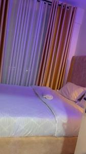 1 cama frente a una ventana con cortinas en cate havens, en Nairobi