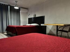 a bedroom with two beds with red sheets and a table at Hotel Miramar - La Paz in La Paz +20 photos