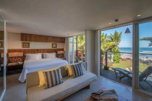 a bedroom with a bed and a balcony with the ocean at Hotel Spa Nau Royal in Camburi