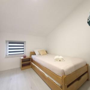 a white bedroom with two beds and a window at Apartman Tony in Međugorje