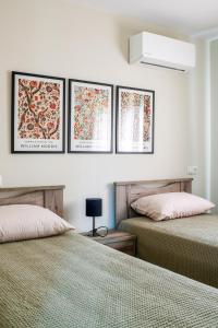 twee bedden in een slaapkamer met drie foto's aan de muur bij Villa Natura in Kavala