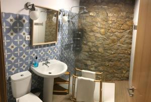 a bathroom with a toilet sink and a stone wall at El Rincón De Cabello in Sierra