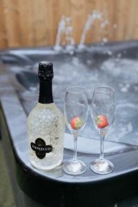 eine Flasche Wein und drei Weingläser auf einem Tablett in der Unterkunft Marine Cottage 1 - With Private Hot Tub in Newbiggin-by-the-Sea