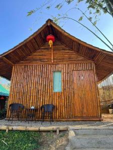 a hut with two chairs and a table in front of it at เฉินหลงเกสท์เฮ้าท์ บ้านรักไทย แม่ฮ่องสอน in Ban Rak Thai