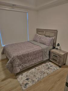 a bedroom with a bed and a night stand with a lamp at A stylish 2 BDR with a blend of cozy and peace! in Calgary