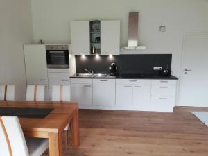 une cuisine avec des armoires blanches et une table en bois dans l'établissement Rosensteinferien, à Mögglingen