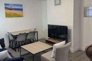 West BoldonにあるBungalow - Sleeps 2 - Parking - Gardenのテレビとテーブルと椅子のあるリビングルーム