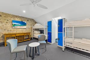 a room with two bunk beds and two chairs at London Gate Backpackers Hotel in Sydney