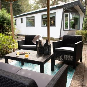 a patio with four chairs and a table with drinks on it at Celisa S Häuschen in Hoenderloo