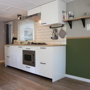a kitchen with white cabinets and a microwave at Celisa S Häuschen in Hoenderloo +9 photos