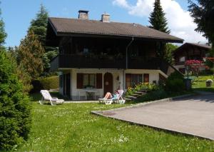 a woman sitting in chairs in front of a house at Akalei in Aeschi