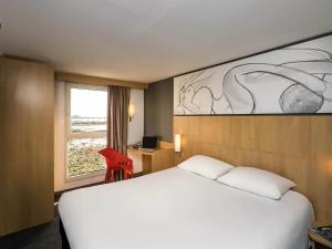 a hotel room with a white bed and a window at Ibis Roscoff in Roscoff +33 photos