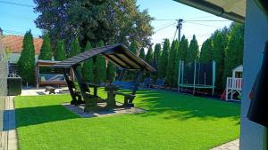 a park bench with a roof on the grass at Eleven Apartman Agárd in Gárdony +2 photos