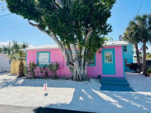 a pink house with a tree in front of it at Playa Esmeralda Cottage! Add Golf Cart!! in Bradenton Beach