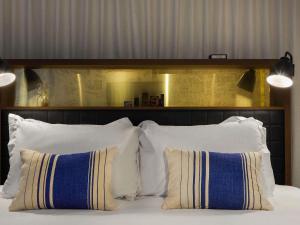a bed with white pillows and a wooden headboard at INK Hotel Amsterdam - MGallery Collection in Amsterdam +89 photos