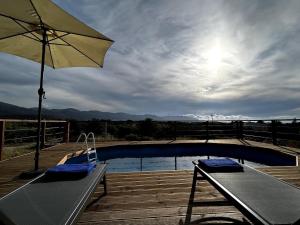 a pool with an umbrella and two benches and a table at Small villa with pool DOXA PETRA in Sísion