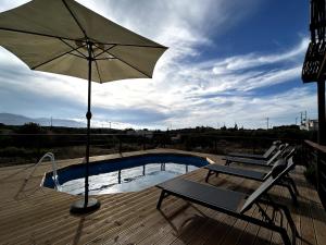 a patio with two chairs and an umbrella next to a pool at Small villa with pool DOXA PETRA in Sísion