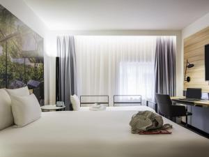 a bedroom with a large white bed and a desk at Novotel Den Haag City Centre in The Hague